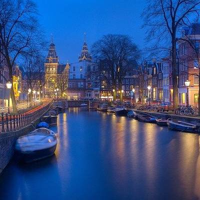 Evening view of Amsterdam canal with boats and lights.