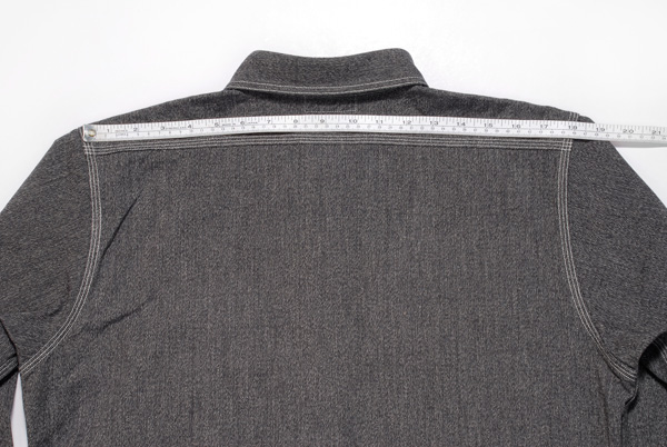 Measuring shirt shoulder width with ruler.