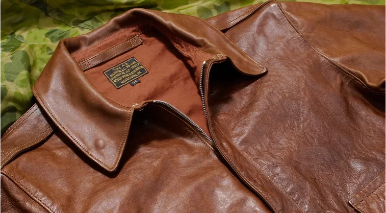 Brown leather jacket on green camouflage fabric.