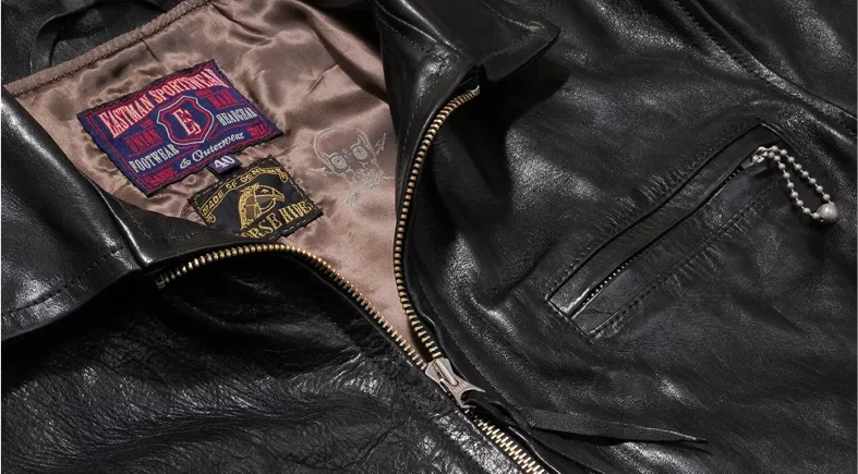 Black leather jacket with vintage patches and zipper.